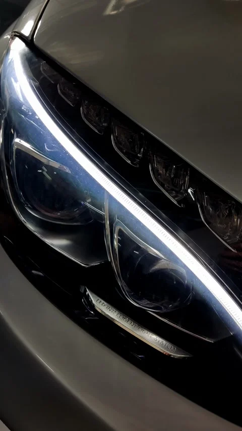 Cinematic close-up of a glowing LED headlight on silver car Stock Footage 334128864