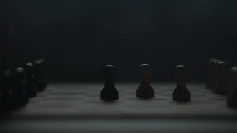 Cinematic close-up of a hand moving a chess piece in a dark atmospheric room. Video stock 333295204