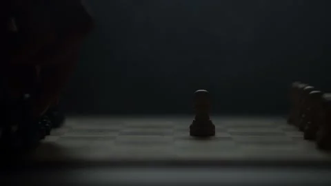 Cinematic close-up of a hand moving a chess piece in a dark atmospheric room. Video stock 333295209