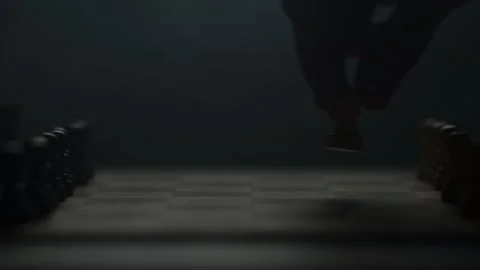 Cinematic close-up of a hand moving a chess piece in a dark atmospheric room. Video stock 333295210