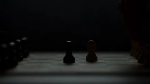 Cinematic close-up of a hand moving a chess piece in a dark atmospheric room. Video stock 333295226