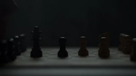 Cinematic close-up of a hand moving a chess piece in a dark atmospheric room. Video stock 333295236