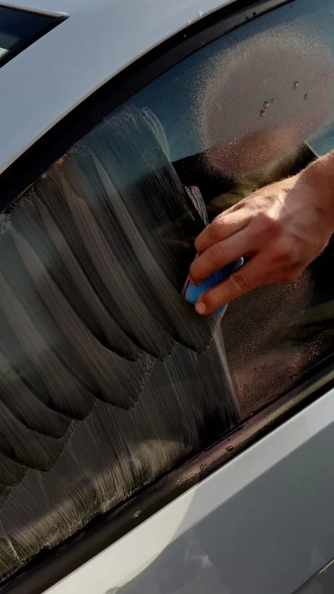 Cinematic close-up of a hand scrubbing car window with foam Stock Footage 334128958