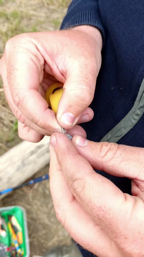Cinematic close-up of hands attaching a lure to fishing line Stock Footage 334229013