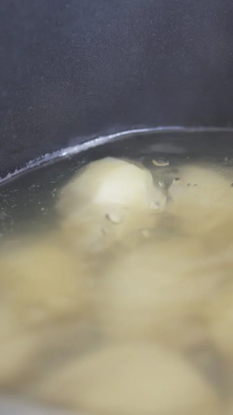 Cinematic close-up of potatoes boiling in bubbling water with steam Stock Footage 333973361