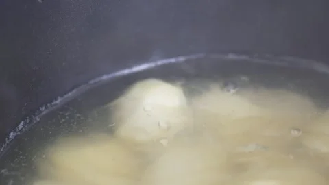 Cinematic close-up of potatoes boiling in bubbling water with steam Stock Footage 333973556