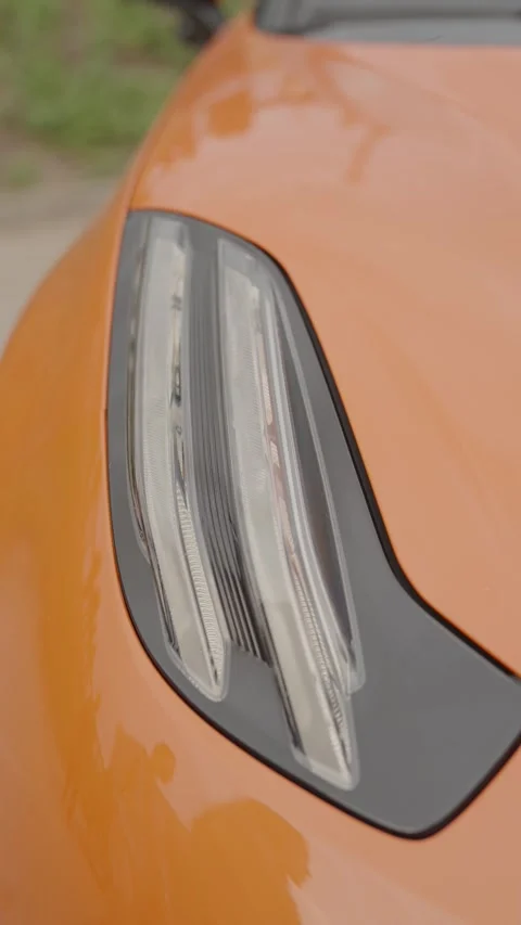 Cinematic close-up of sleek LED headlight on orange sports car Stock Footage 335076233