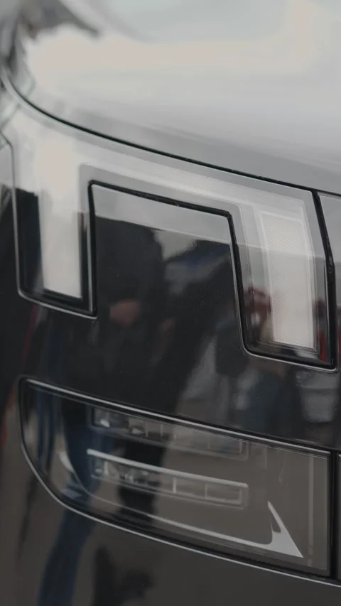 Cinematic close-up of sleek modern black car headlights turning on Stock Footage 335076246