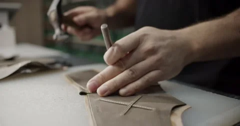 Cinematic close up view of master makes holes in leather piece to make shoes in Stock Footage 200127251