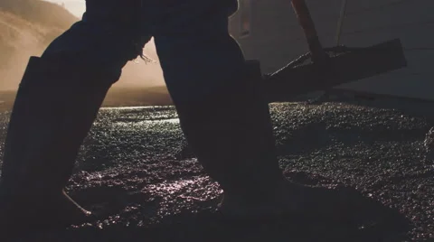 Cinematic closeup of construction worker's feet while spreading concrete Stock Footage 55156473