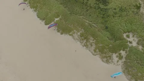 Cinematic drone descent with upward camera tilt following paragliders soaring Stockbeeldmateriaal 333989663