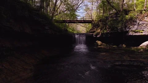 Cinematic drone flight backwards from bridge over larger waterfalls Stock Footage 147987680