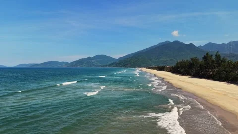 Cinematic drone flight over a pristine empty beach with mountain backdrop 4K Stock Footage 336598501