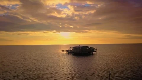 Cinematic drone flight past old water cabin during vibrant golden hour Stock Footage 345979266