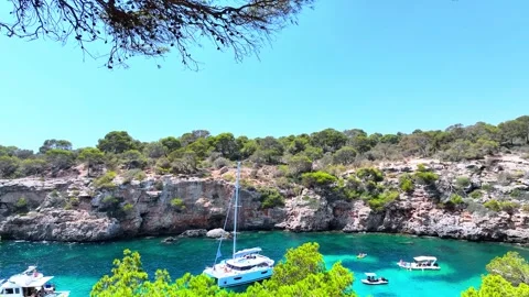 Cinematic Drone Flight Through Trees Over Cala Pi Bay with Boats, Mallorca Video stock 304679420