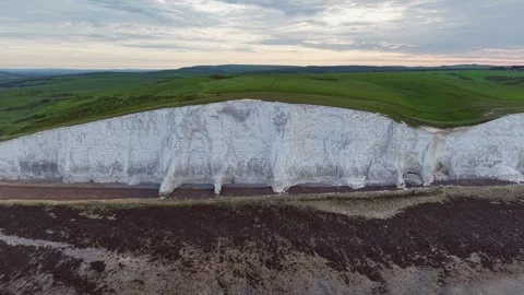 Cinematic drone gliding toward towering chalk cliff over rocky beach Stock Footage 309764396
