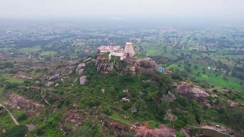 A cinematic drone pan view of Melkote temple on top of hill surrounded by s.. Stock-Footage 344877783
