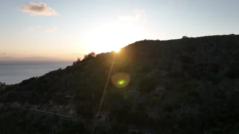 Cinematic drone pullback at sunset, opening from the tree-covered slope to the Stock Footage 331025719