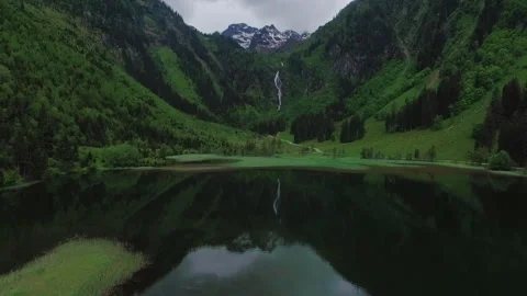 Cinematic Drone Push In Over Alpine Lake with Mountain Reflection and Waterfall Stock Footage 336802036