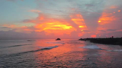 Cinematic Drone Push Over Ocean at Fiery Tropical Sunset With Distant Surfer Stock Footage 339310872