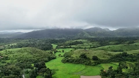 Cinematic drone view of lush mountains, farmlands, a valley, curvy road, an.. Video stock 314208482