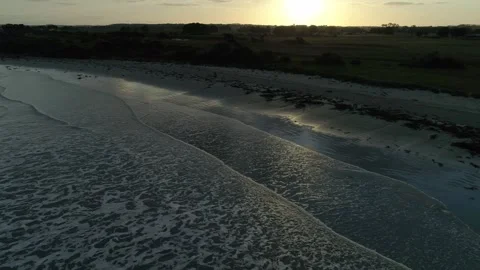 Cinematic drone view of peaceful waves crashing on the beach at sunset Stock Footage 331275572