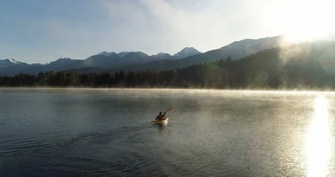 Cinematic Follow Shot Of A Man Paddling Across A Mountain Lake At Sunrise Vídeo Stock 101045243