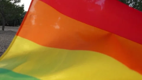 Cinematic footage of non-binary young guy holding a flying rainbow flag 스톡 동영상 250471731