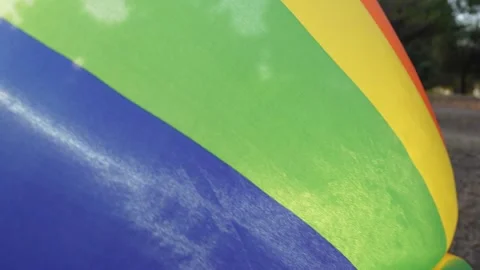 Cinematic footage of non-binary young guy holding a rainbow flag at sunset Stock Footage 250471932