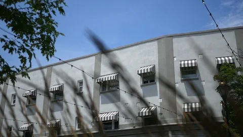 Cinematic Foreground grass blowing in front of white bricked apartment building Vidéo 112244210