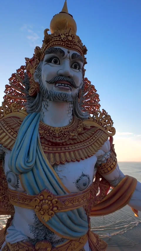 Cinematic FPV drone flight around giant oceanfront statue at sunset in Bali 動画素材 340169356