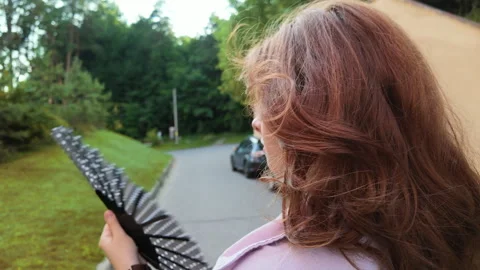 Cinematic girl using a folding hand fan during an intense summer heatwave Stock Footage 340130164