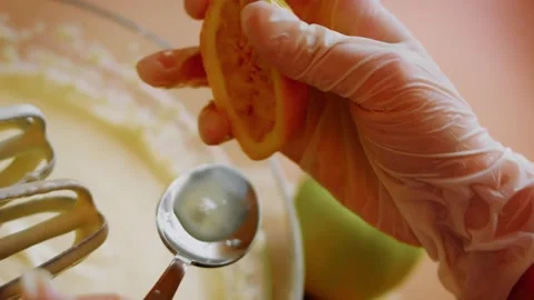 Cinematic gloved hand adding citrus zest to cream mixture in low angle, 4K Stock Footage 341115989
