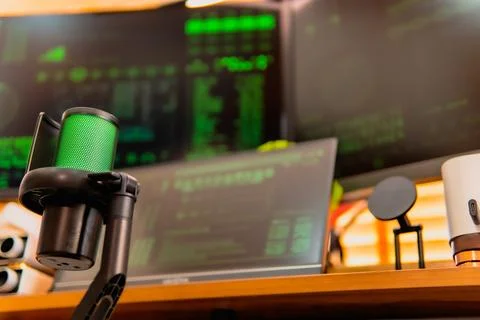Cinematic hacker workspace with green code screens and microphone setup Stock Photos