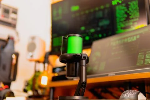 Cinematic hacker workspace with green code screens and microphone setup Stock Photos