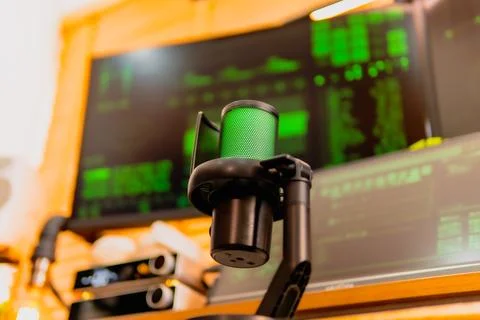 Cinematic hacker workspace with green code screens and microphone setup Foto stock