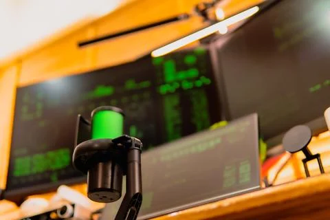 Cinematic hacker workspace with green code screens and microphone setup Stock Photos