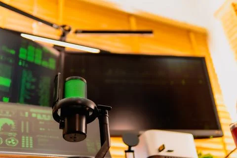 Cinematic hacker workspace with green code screens and microphone setup Foto stock