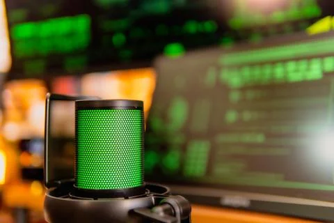 Cinematic hacker workspace with green code screens and microphone setup Foto stock
