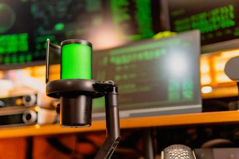 Cinematic hacker workspace with green code screens and microphone setup Stock Photos