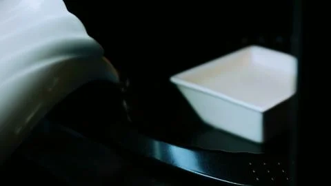 Cinematic ingredient study of carrying the square flan mold toward the oven Foto stock