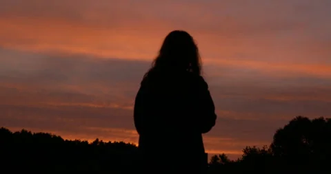 Cinematic landscape with warm sunset tones, silhouette of woman 스톡 동영상 340291418