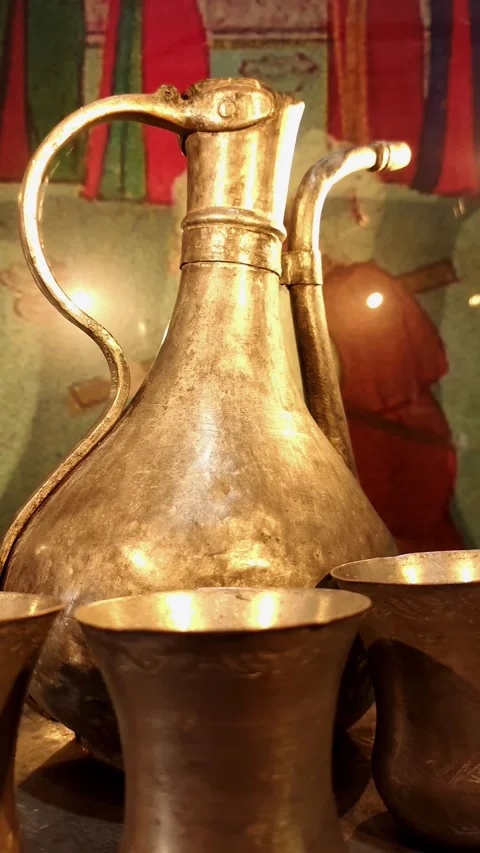 Cinematic left-to-right pan of an ancient metal pitcher and matching cups under Vídeos de archivo 334108366