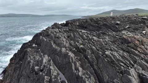 Cinematic low-angle aerial shot along cliffs with a lighthouse, Ireland. Stock Footage 342733534