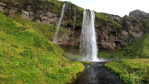 Cinematic low-angle shot of a stream and powerful waterfall in 4K Stock Footage 334809059