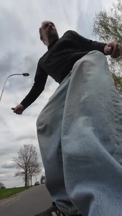 Cinematic low-angle view looking upward at a middle-aged skateboarder cruising Stockbeeldmateriaal 335276140