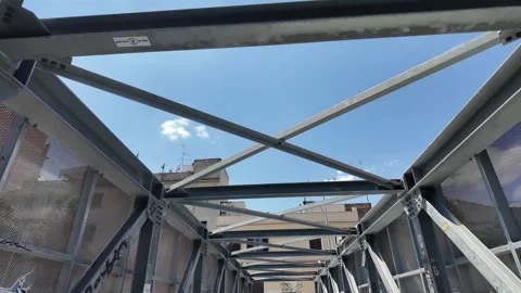 Cinematic low angle view of a modern geometric metal pedestrian bridge Stock Footage 341426763