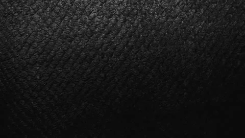 Cinematic macro pan shifts light across dark black textured knit fabric revealin Stock Footage 337025576