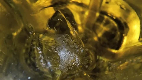 Cinematic macro shot of whisky bubbles rising around ice cubes in a glass. Stock Footage 331570061