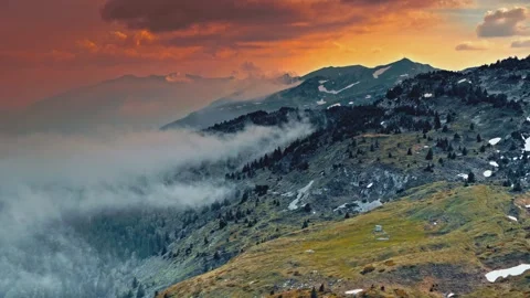 Cinematic mountain range with rolling fog during a vibrant orange sunset Stock Footage 345484978
